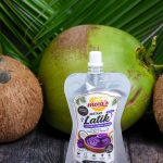 Armand Ansaldo Photography UntiSingle pouch of Meea's Instant Latik Coconut Caramel Spread centered between whole coconuts on a rustic wooden tabletled 0000 207